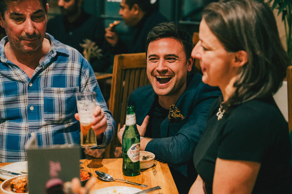 Friends laughing over drinks at a table at The Granary