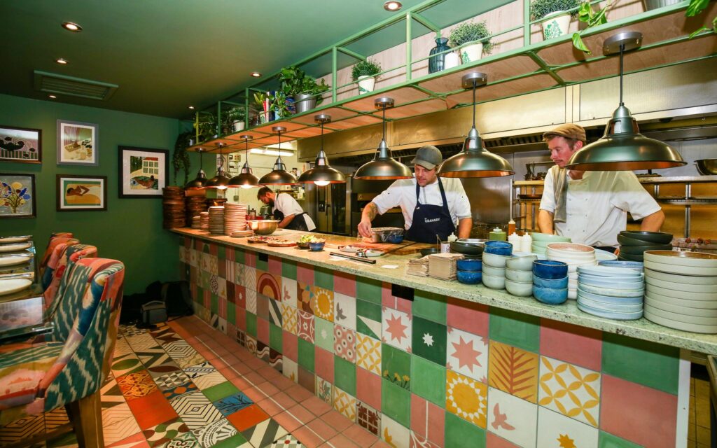 Chefs at work in the open kitchen at The Granary, behind a counter faced with colourful patterned tiles