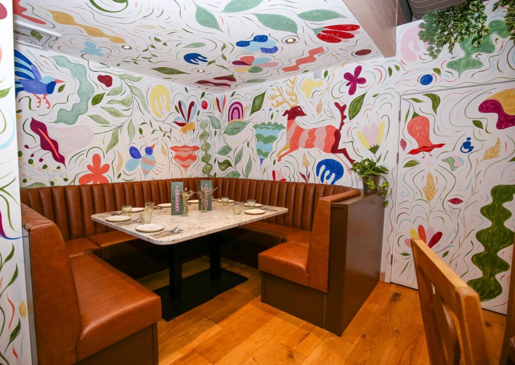 A leather booth surrounded by hand-painted murals of birds, animals and plants at The Granary
