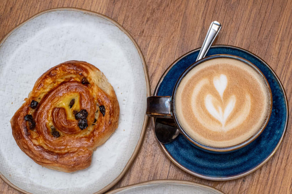 A pastry and a latte on a wooden table at The Granary