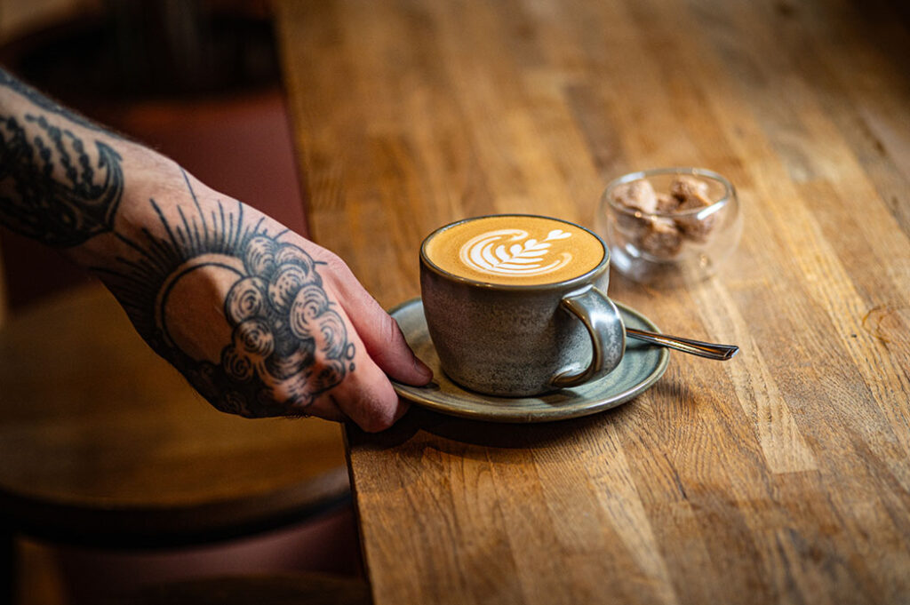A latte being set down on the wooden bar at The Granary