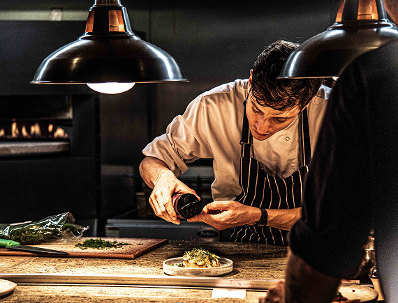 A chef finishing a dish at the kitchen pass at The Granary