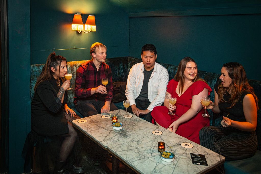 Friends celebrating with cocktails around a table in The Granary Club